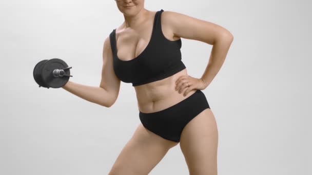आकर्षक गोल-मटोल महिला डंबबेल के साथ व्यायाम कर रही है। सफेद पृष्ठभूमि पर वजन के साथ काकेशियन लड़की प्रशिक्षण। धीमी गति वीडियो . — स्टॉक वीडियो