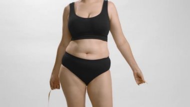 Tam şekilli kadın karnını ölçüyor. Beyaz arka plan stüdyo yüksek kaliteli video.