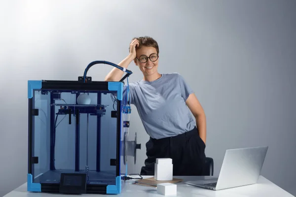 Młoda, szczęśliwa, atrakcyjna kobieta przedsiębiorca z drukarką 3D produkującą prototypy. Proces drukowania 3D. Poziomy obraz zdjęć wysokiej jakości środowiska pracy. — Zdjęcie stockowe