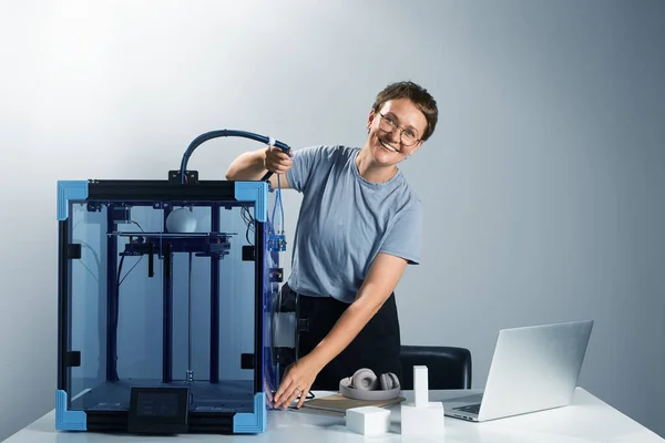 Młoda, szczęśliwa, atrakcyjna kobieta przedsiębiorca naprawiający tubę na drukarce 3D, aby stworzyć prototyp. Przygotowanie do druku 3D. Poziomy obraz zdjęć wysokiej jakości środowiska pracy. — Zdjęcie stockowe