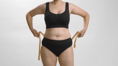 Belinde bant olan aşırı kilolu beyaz bir kadın. Yine de yüksek kaliteli video..