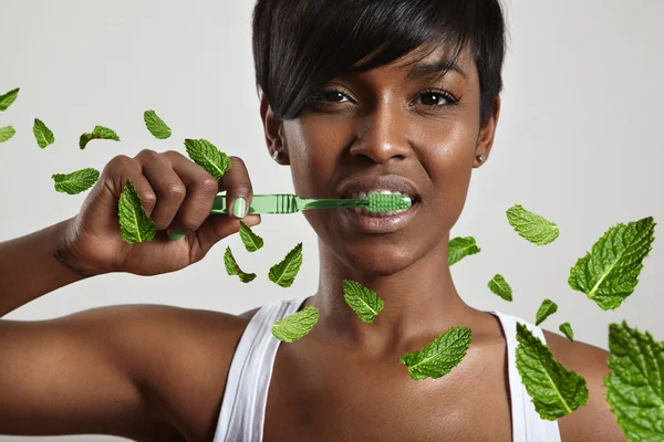 Mujer limpiando dientes con hojas de menta — Foto de Stock