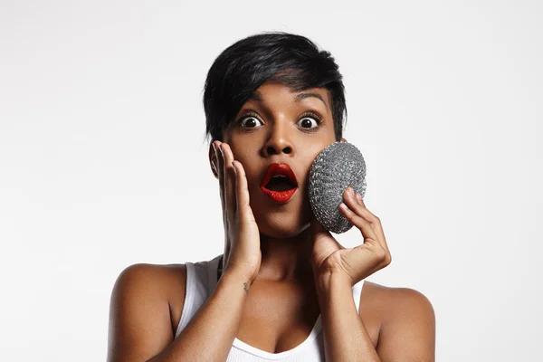 Surprised woman with metalick sponge on a face — Stock Photo, Image