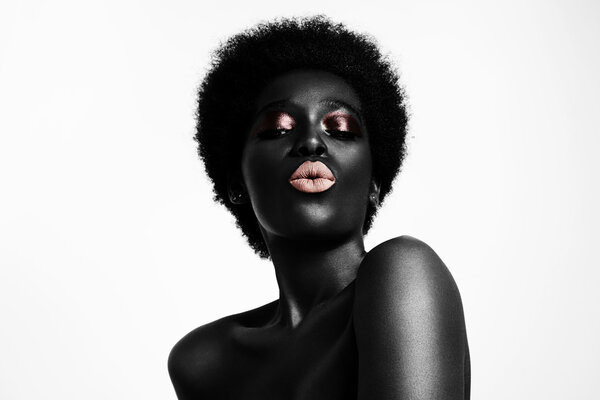 Black woman with beige lips sending kiss, studio shot
