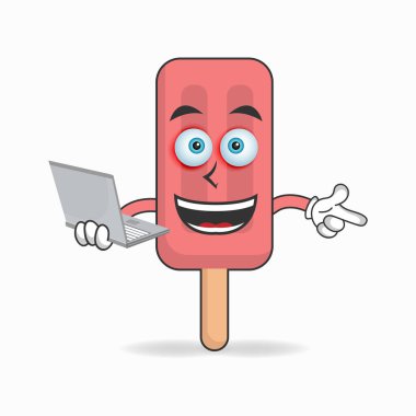 Sağ elinde dizüstü bilgisayarı olan Kırmızı Dondurma maskotu..