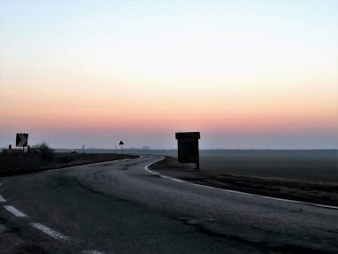 Kışın bir köy yolundan gün batımında sisli tarlaların canlandırıcı görüntüsü