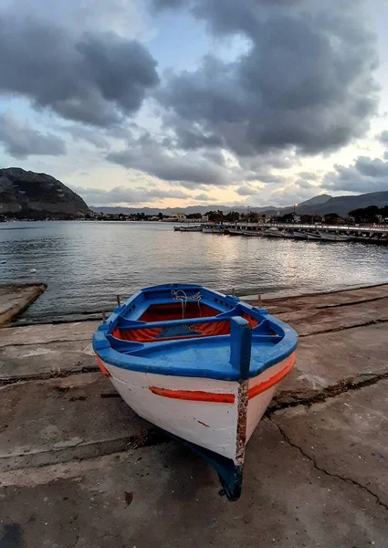 evocative image of fishing boat at the beach by the sea at sunset with bad weather