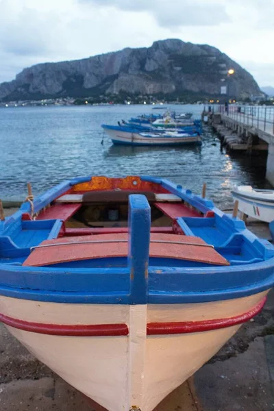 evocative image of fishing boat pulled ashore in harbor with other boats moored in the background and bad weather in the evening