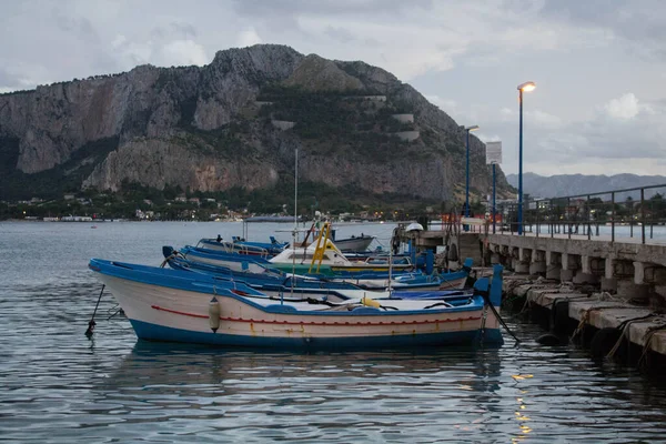 evocative image of fishing boats moored in the harbor with the coastline in the background and bad weather in the evening