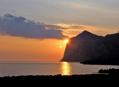 Güneş ufuktan yükselirken denizin üzerinde güneşin doğuşunu anımsatan bir görüntü.