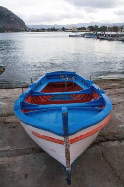 Limanda kıyıya çekilen balıkçı teknelerinin canlandırıcı görüntüsü. Arka planda demirlemiş diğer tekneler ve akşam kötü hava koşulları.