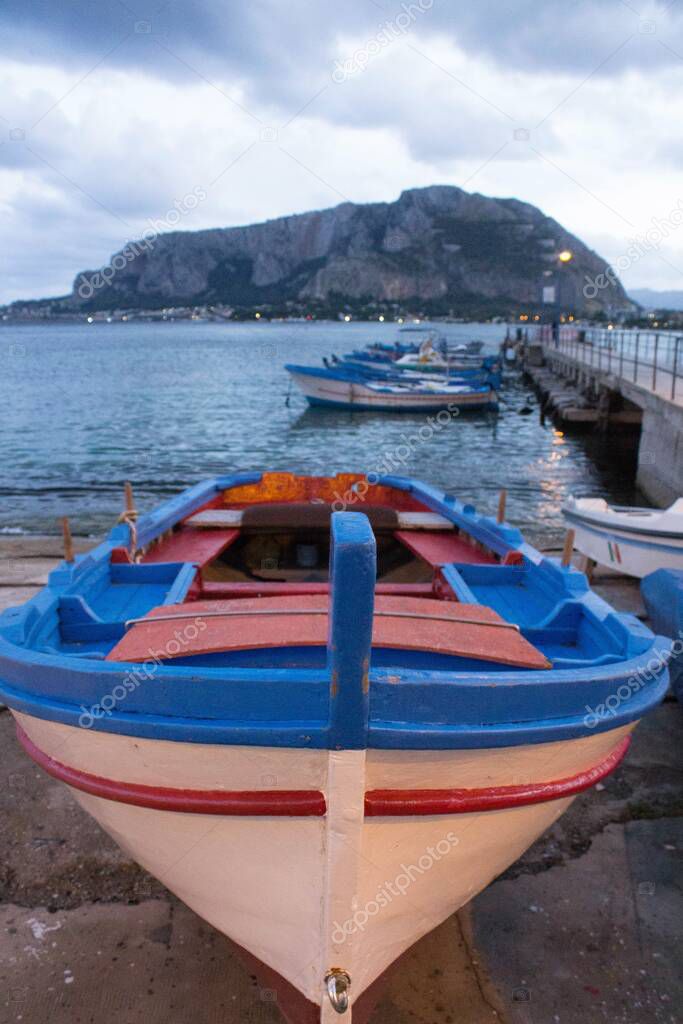 evocative image of fishing boats pulled ashore in harbor with other boats moored in the background and bad weather in the evening