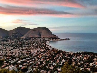Mondello, Sicilya, sahil manzarası ve arkasında Monte Pellegrino 'nun olduğu güzel mavi gökyüzünün altında bir deniz kenarı kompleksi.