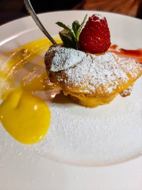 Beyaz tabakta servis edilen çilekli muhallebi tatlısı.