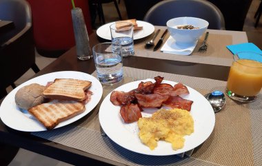 Avrupa kahvaltısı çırpılmış yumurta, tütsülenmiş domuz pastırması, tost ve tatlı.