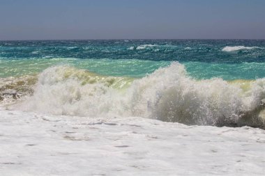 Kumlu bir sahilin canlandırıcı görüntüsü. Bir sürü rengi ve berrak gökyüzü var.