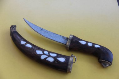 Tahta masanın üzerinde yaprak olan hançer.