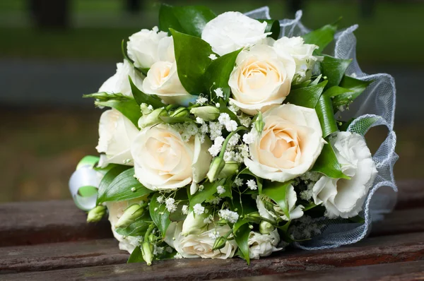 Buquê de casamento de rosas creme e folhas verdes no banco de madeira — Fotografia de Stock