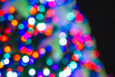 Noel ağacının boşluklu sıcak ışıkları gece gökyüzüne karşı, odaklanmamış arka plan