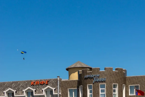 Skydivers vlucht over gebouw op Tanai vliegveld - locatie voor parachutespringen en tandem jumping wedstrijden voor iedereen — Stockfoto