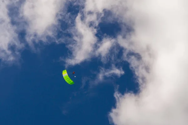 Green parachute against the background of blue sky and clouds — Stock Photo, Image