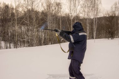 Bir adam ateş ediyor, duman namludan çıkıyor.