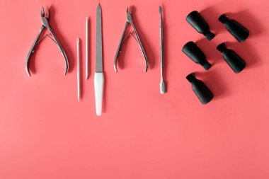 Pembe arka planda manikür ve pedikür için teçhizatın üst görüntüsü.
