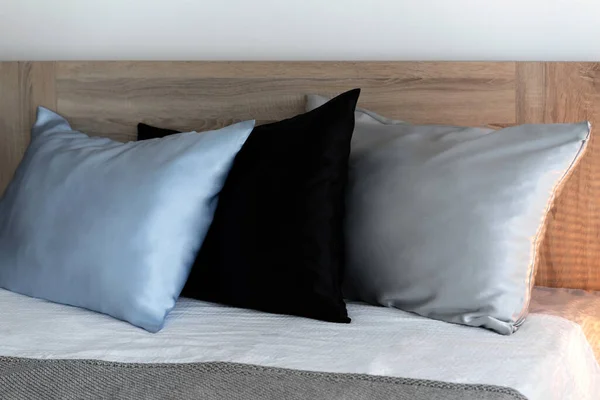 Três travesseiros em fronhas de seda na cama. — Fotografia de Stock