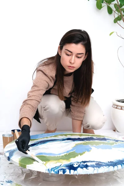 Μια νεαρή γυναίκα δημιουργεί έναν πίνακα χρησιμοποιώντας τεχνική υγρής τέχνης. Royalty Free Εικόνες Αρχείου