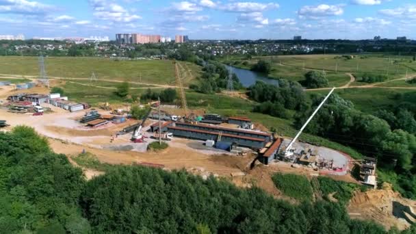 Equipe de construção pavimentando uma nova estrada e ponte através do córrego - metragem de drone — Vídeo de Stock