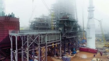 Rafineri işçileri boru hattını onarıyor, sisli bir günde kaynak yapıyorlar. İnsansız hava aracı görüntüleri