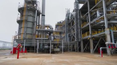 Petrol rafinerisi. Ön plandaki çelik yapılar. Arka planda baca.