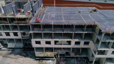 Building under construction at a construction site. Reinforced walls prepared for concreting. Internal floors are visible through the window openings. The walls are lined with bricks.