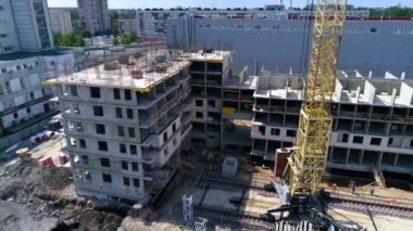 Movement from unfinished building. Workers are building a monolithic house and installation of reinforcing steel for concrete casting. Yellow tower crane and building materials at construction site.