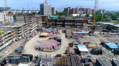 Construction of a new residential complex. City is growing and rebuilding new areas. Construction site with tower cranes, rebars, building materials. Construction of a monolithic house is in progress.