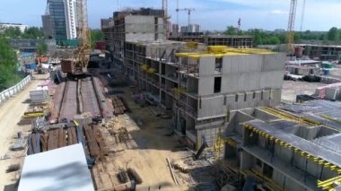 Kamera yukarı hareket ediyor. Monolitik bir apartman inşaatı devam ediyor. İnşaat alanında, bina iskeletinin önünde rayların üzerinde bir vinç ve takviye çubukları var. Yaz güneşli bir gün.