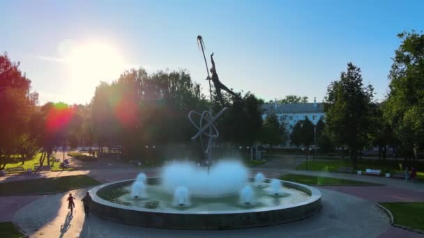 Fonte e monumento a Gagarin em raios de pôr do sol. Criança monta uma bicicleta — Vídeo de Stock