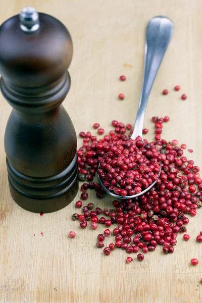 Pink peppercorns, Walnut Pepper Mill and Pink peppercorns in spoon on wooden table