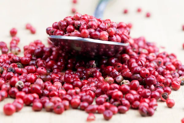 Pink peppercorns, Pink peppercorns in spoon on wooden table