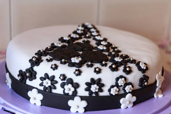 a cake with sugar paste decorated with brown and white flowers