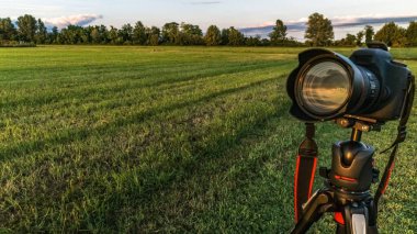 Gün batımını fotoğraflamak için tripodun üzerindeki SLR kamerası.