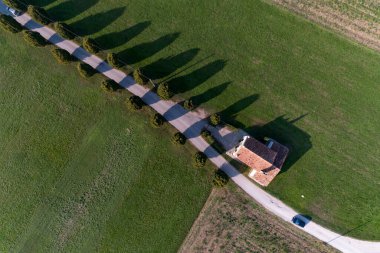 Hava manzaralı ağaçlarla kaplı bir sokakta bir kilise ve ağaçların gölgeleri