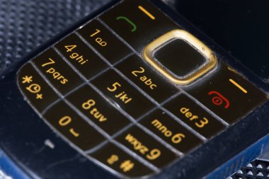 Kırık eski cep telefonu, sarı anahtarlı siyah cep telefonu.