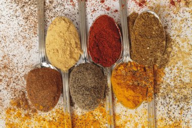 Tahta arka planda kaşıklardaki çeşitli baharatlar
