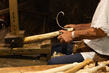 Bir ahşap işçisinin elleri torna tezgahında bir odun parçasını şekillendirmek için keski kullanır..