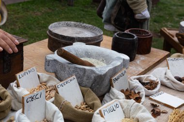 Çeşitli tahıl, fasulye ve tohumlardan oluşan sayısız küçük çuval, her biri el yazısıyla yazılmış bir etiketle bir pazar masasında sergileniyor..