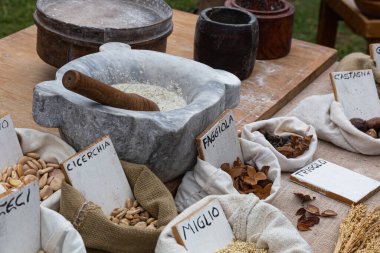 Çeşitli tahıl, fasulye ve tohumlardan oluşan sayısız küçük çuval, her biri el yazısıyla yazılmış bir etiketle bir pazar masasında sergileniyor..