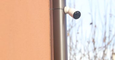 Kırmızı Duvara monte edilmiş Beyaz Kablosuz Güvenlik Kamerasının yakın plan görüntüsü.