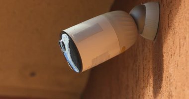 Kırmızı Duvara monte edilmiş Beyaz Kablosuz Güvenlik Kamerasının yakın plan görüntüsü.