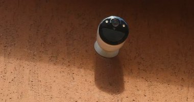 Kırmızı Duvara monte edilmiş Beyaz Kablosuz Güvenlik Kamerasının yakın plan görüntüsü.